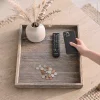 an ottoman tray on top of a coffee table with remote and vase